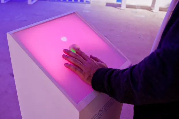 A person placing a finger in a slot of a podium.