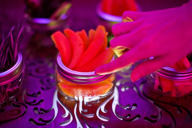 A hand touching the rim of a jar of ingredients.