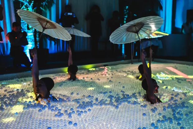 Synchronized swimmers holding up umbrellas while swimming.