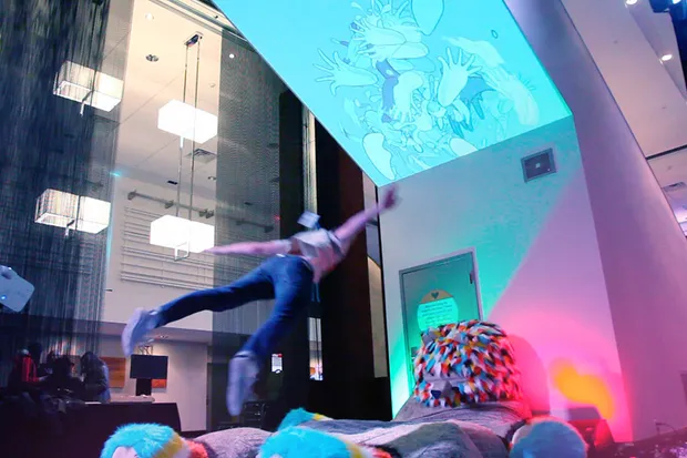 A man mid-flight jumping on a giant stuffed bear.