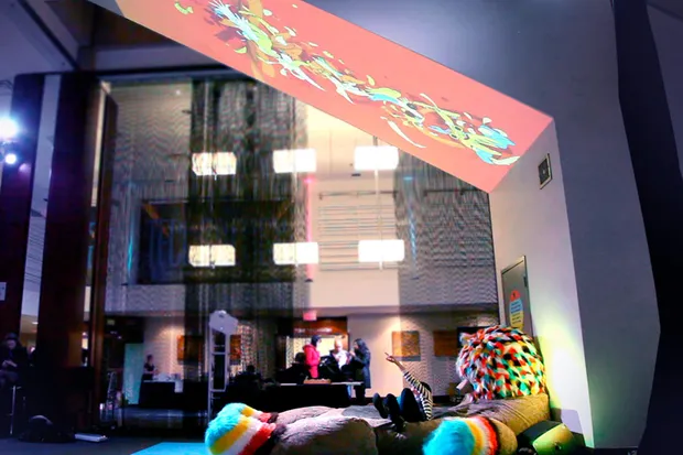A woman on a giant stuffed bear with projections above her.