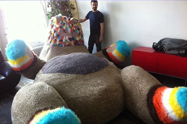 A man indoors next to a giant stuffed bear.