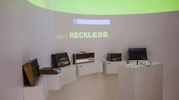 Drum machines in front of a curved wall.